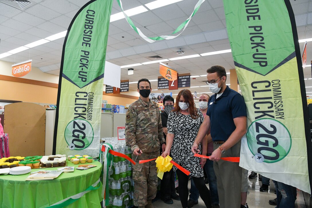 Col. Jeffrey Geraghty, left, commander of Arnold Engineering Development Complex headquartered at Arnold Air Force Base, Tenn., and Brandon Jelson, store director of the Arnold AFB Commissary, cut the ribbon during a ceremony to celebrate the launch of the CLICK2GO online ordering and curbside pick-up service at the commissary, Aug. 3, 2021. Also pictured, holding the ribbon, is Casey Cooper, grocery manager for the commissary. (U.S. Air Force photo by Jill Pickett)