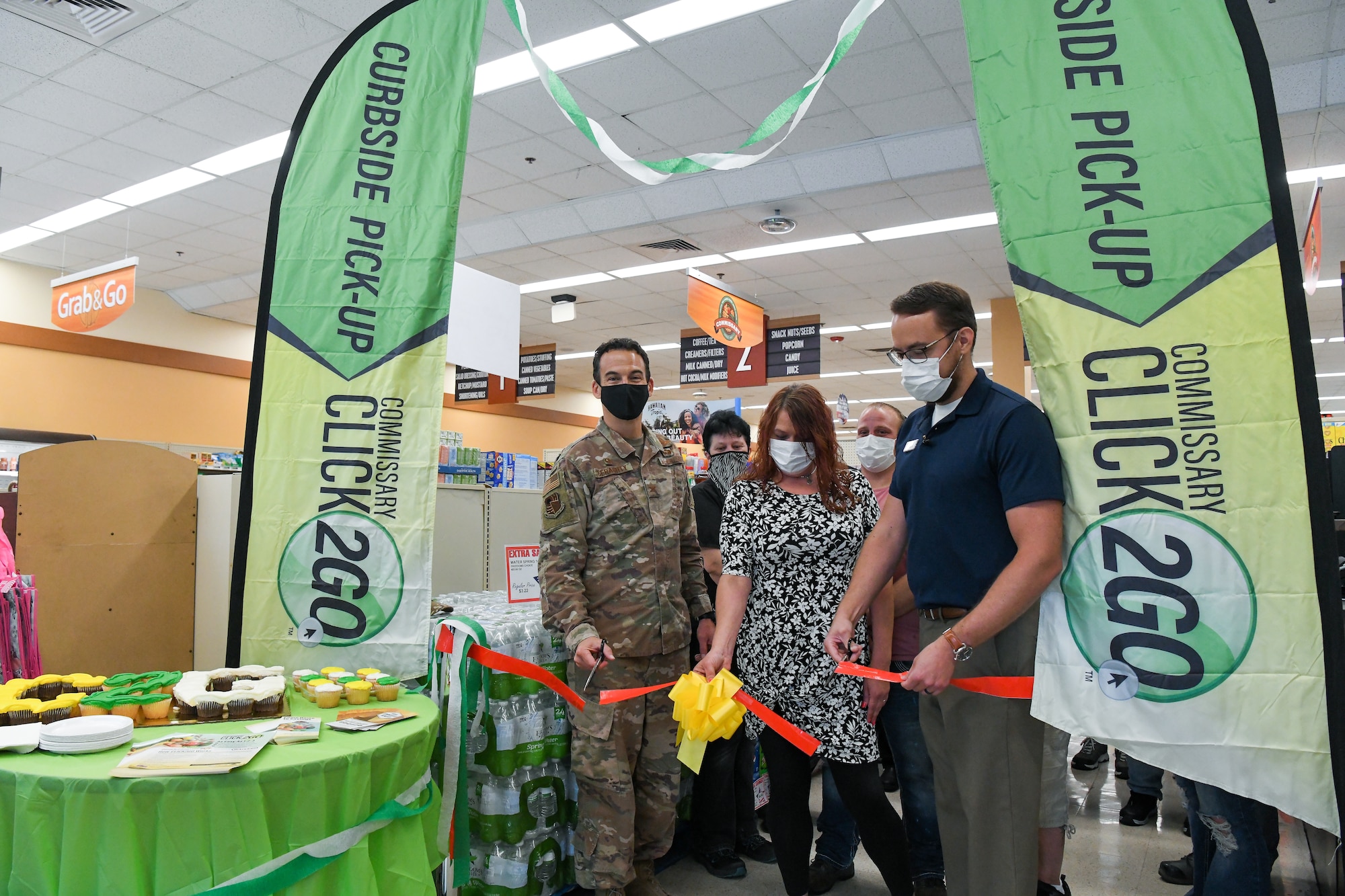 Col. Jeffrey Geraghty, left, commander of Arnold Engineering Development Complex headquartered at Arnold Air Force Base, Tenn., and Brandon Jelson, store director of the Arnold AFB Commissary, cut the ribbon during a ceremony to celebrate the launch of the CLICK2GO online ordering and curbside pick-up service at the commissary, Aug. 3, 2021. Also pictured, holding the ribbon, is Casey Cooper, grocery manager for the commissary. (U.S. Air Force photo by Jill Pickett)