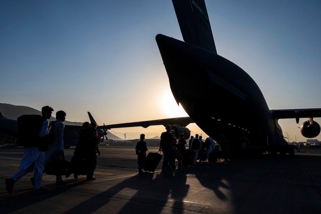 Civilians, shown in silhouette, board an aircraft.