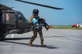 U.S. Army Capt. Alix Idrache, a pilot and future operations planner with the 1st Battalion, 228th Aviation Regiment, Joint Task Force-Bravo, Soto Cano Air Base, Honduras, helps unload a patient from a UH-60 Black Hawk helicopter during a medical evacuation mission in Port-au-Prince, Haiti, Aug. 24, 2021.