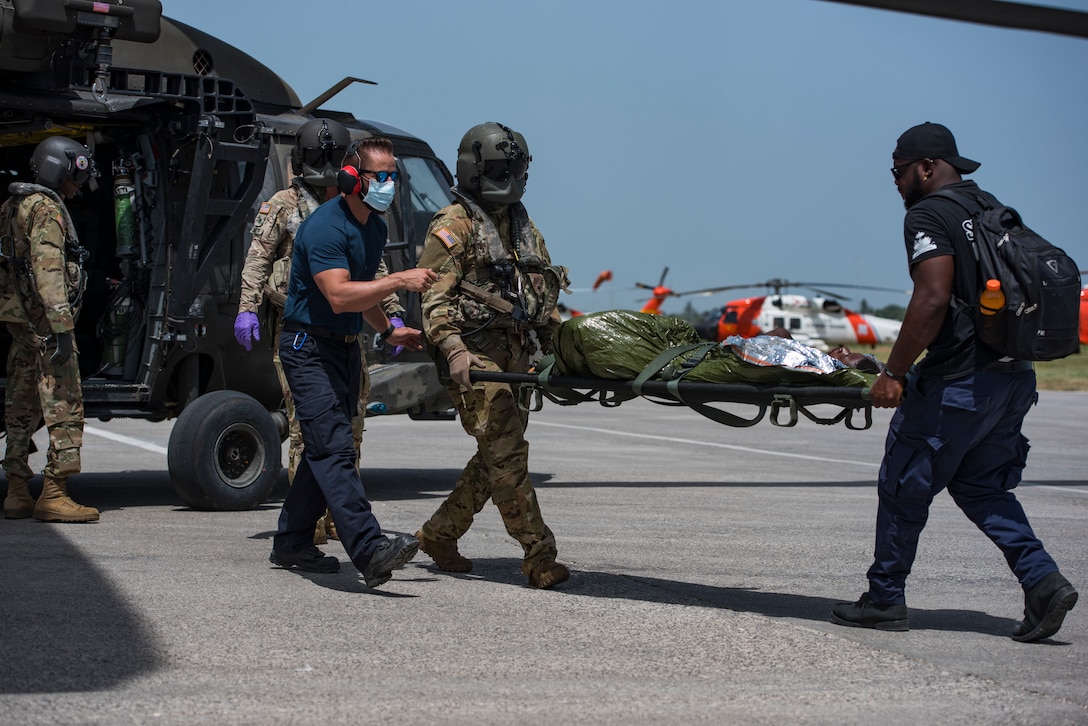 Medical volunteers and aircrew with the 1st Battalion, 228th Aviation Regiment, Joint Task Force-Bravo, Soto Cano Air Base, Honduras, unload patients from a UH-60 Black Hawk helicopter during a medical evacuation mission at Port-au-Prince, Haiti, Aug. 24, 2021.