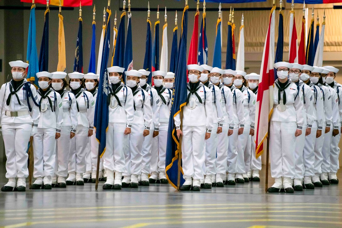 Navy recruits stand in formation; some hold flags.