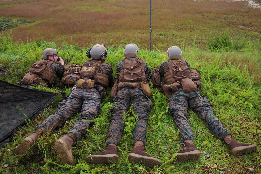 Four Marines lie on the ground.