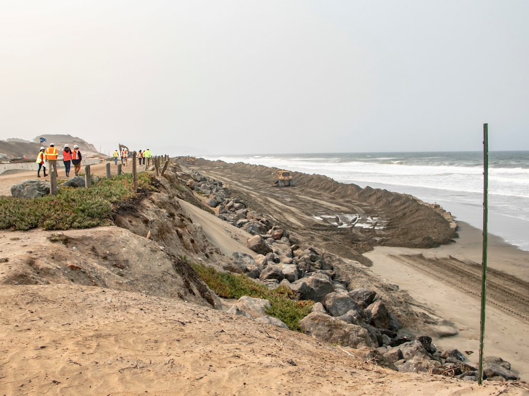 Beach front, ocean, sand being pumped ashore, construction equipment