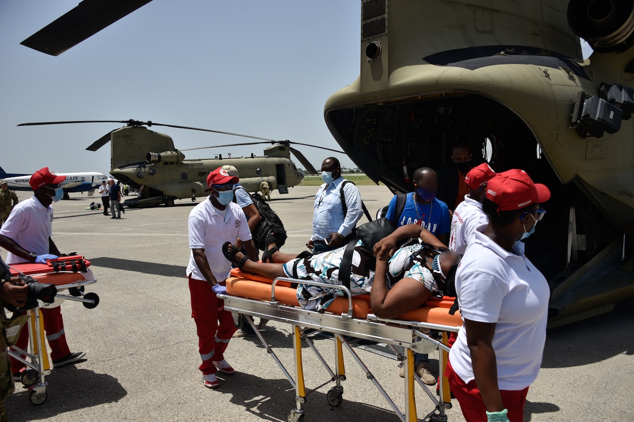 People transport a patient on a stretcher to a helicopter.