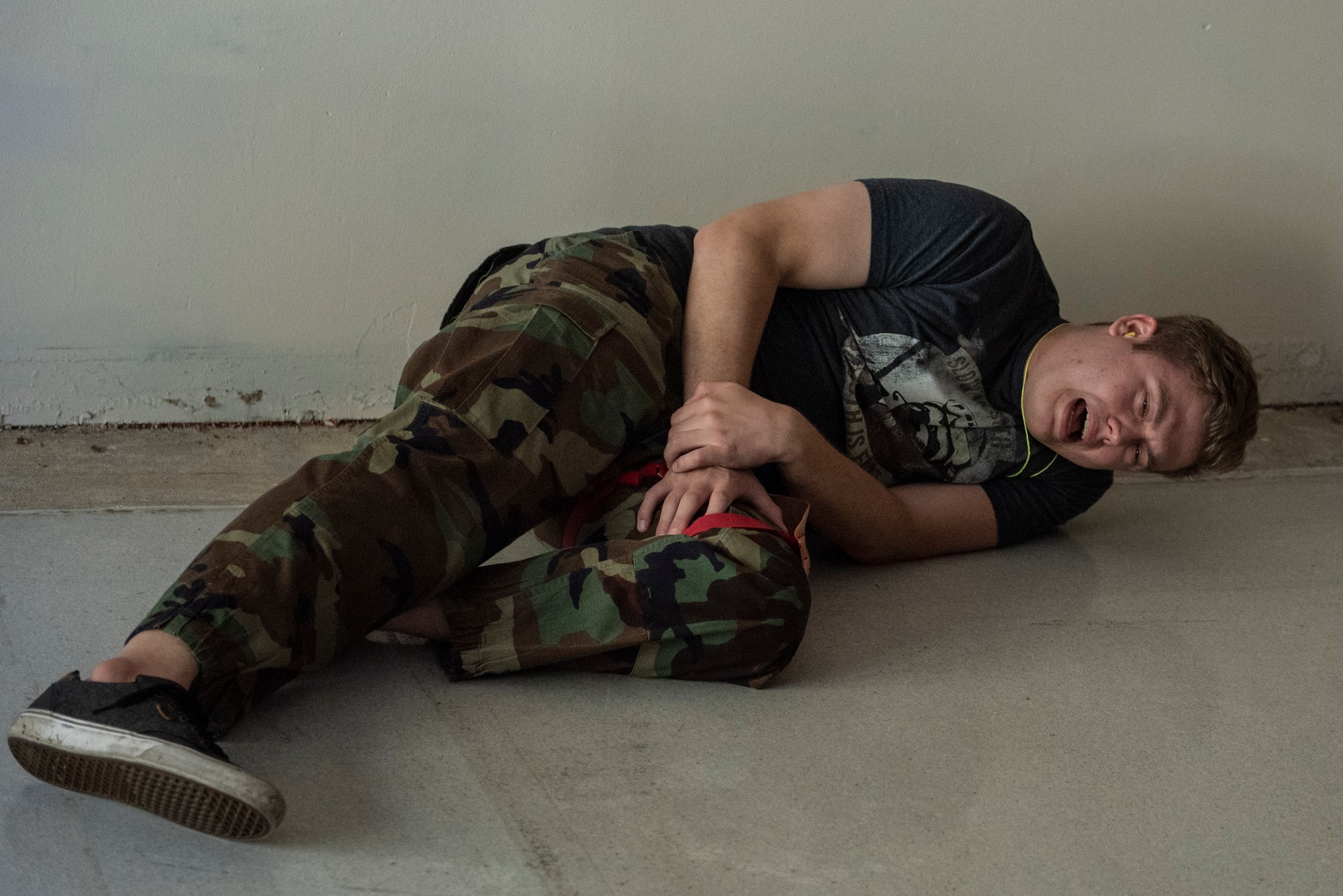 A role-player screams in “pain” after a simulated gunshot wound while waiting for first responders during an active-shooter exercise, Aug. 18 at Wright-Patterson Air Force Base. Readiness exercises are routinely held to streamline unit cohesion when responding to emergencies. (U.S. Air Force photo by Wesley Farnsworth)