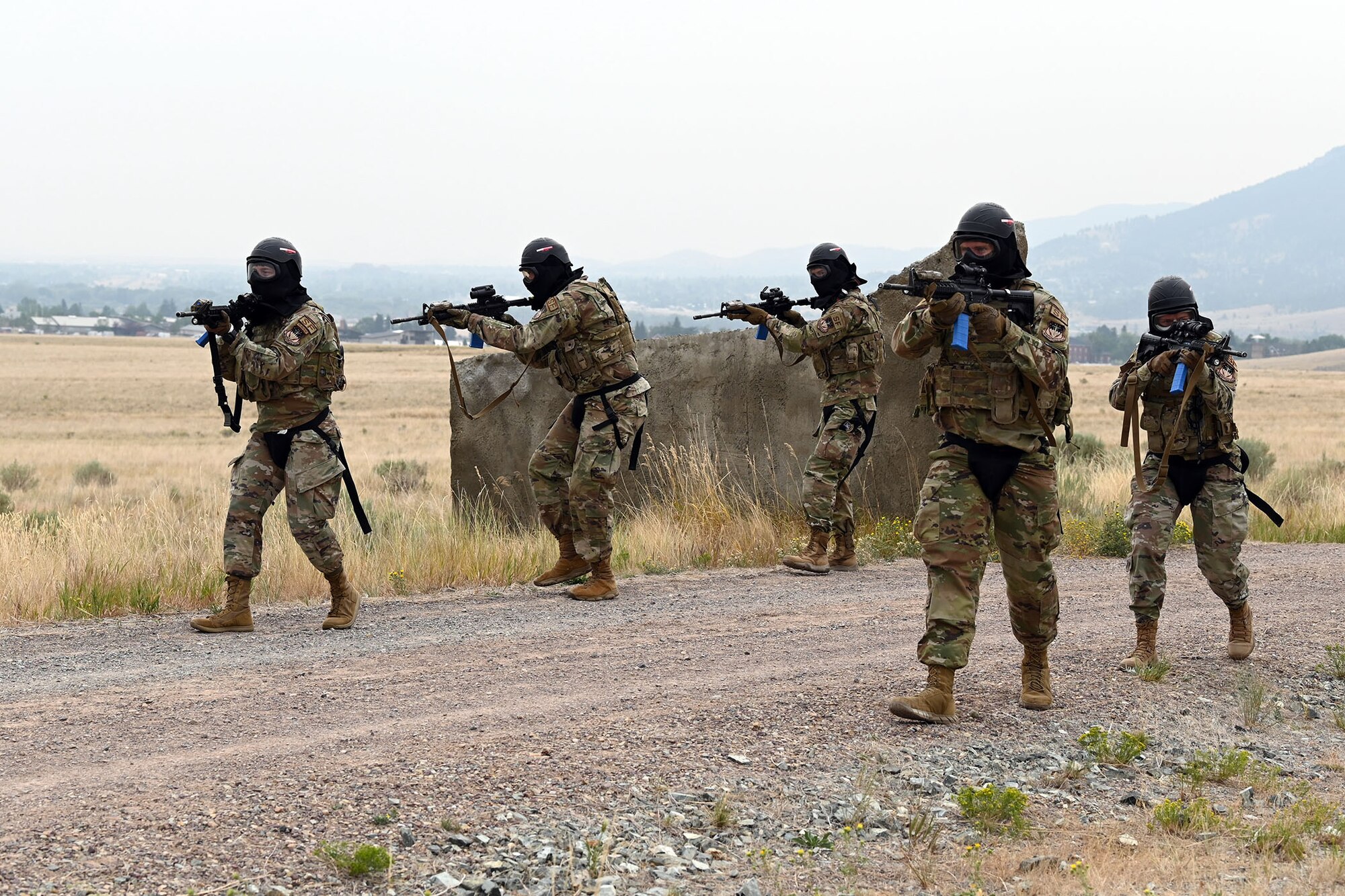 Defenders from the 841st Missile Security Forces Squadron patrol a village road in formation during a breaching exercise Aug. 17, 2021, at the firing range on Fort Harrison, Mont. The defenders’ M4 carbines are armed with blue clips, which contain training ammunition to be used against simulated enemy combatants throughout the exercise. (U.S. Air Force photo by Airman Elijah Van Zandt)