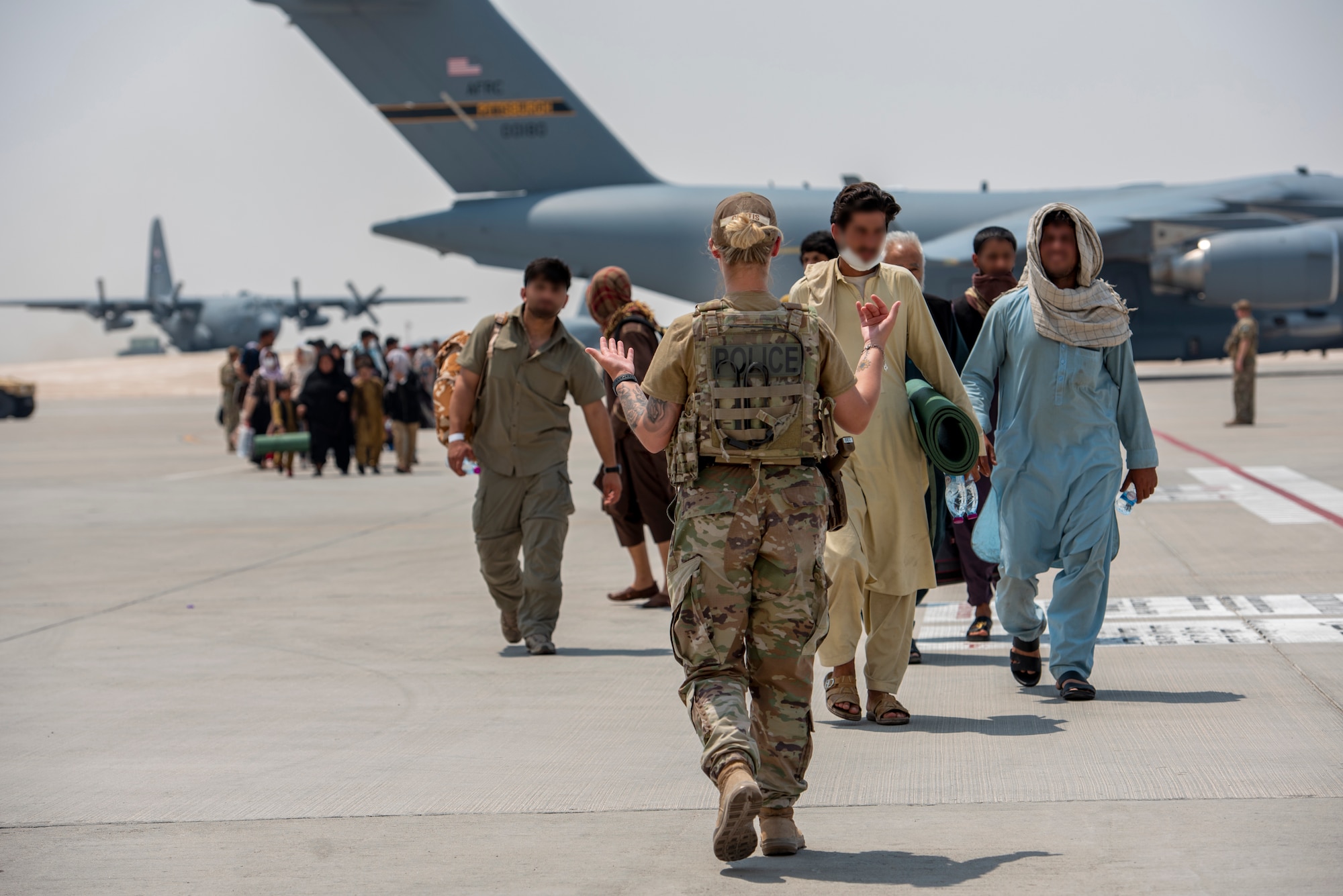 A member from the 379th Air Expeditionary Wing guides qualified evacuees debarking a C-17 Globemaster lll Aug. 23, 2021, at Al Udeid Air Base, Qatar.