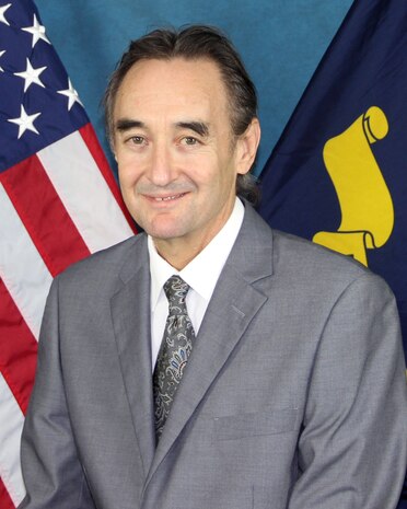 Portrait of Brett Hamilton (SSTM), NSWC Crane in front of an American flag.