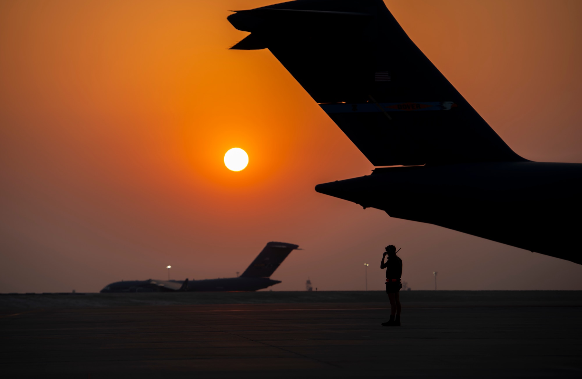 A member from the 379th Air Expeditionary Wing prepares to marshal a C-17 Globemaster lll Aug. 23, 2021, at Al Udeid Air Base, Qatar.