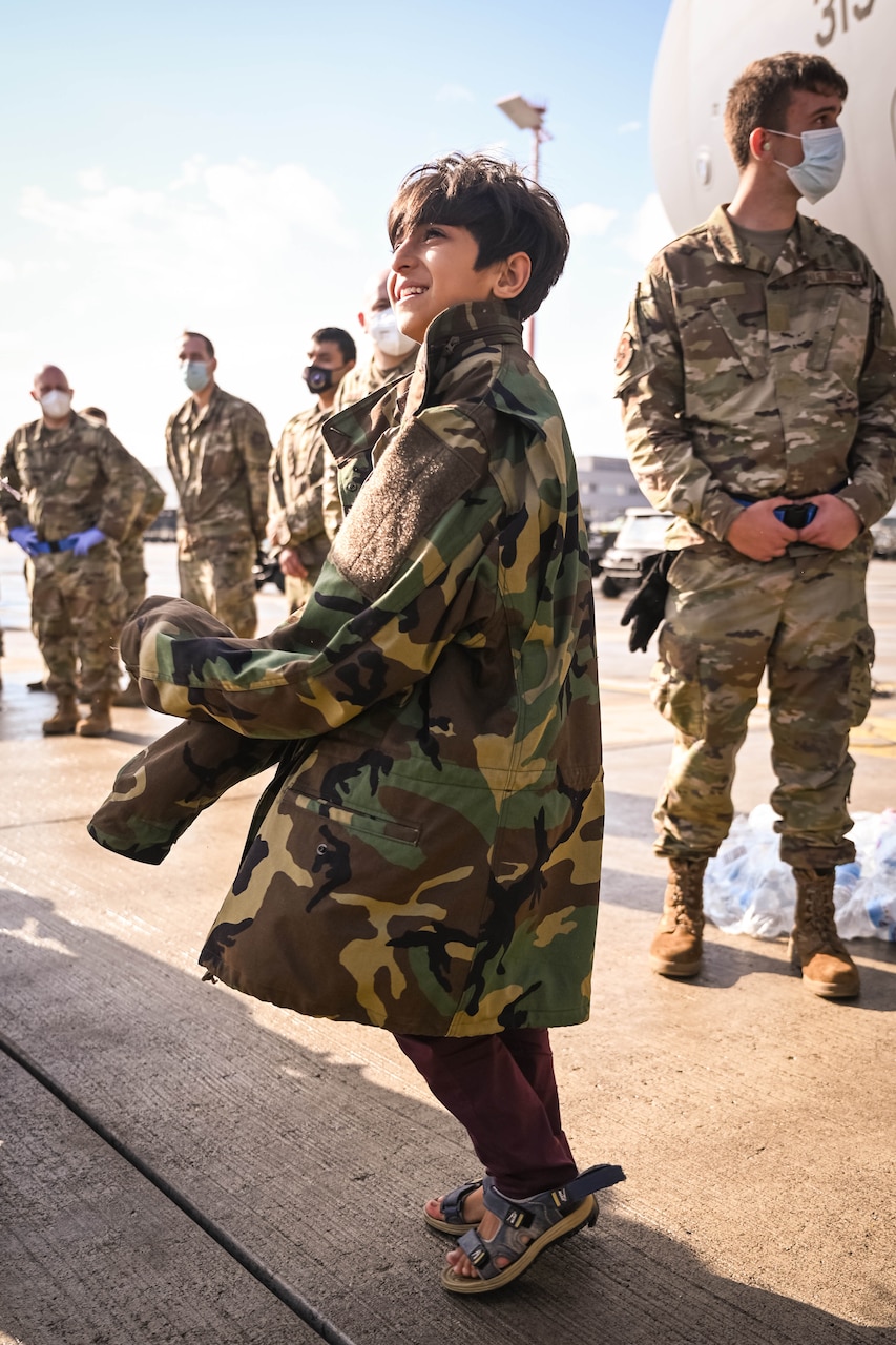 A child wears a military coat that is too large.