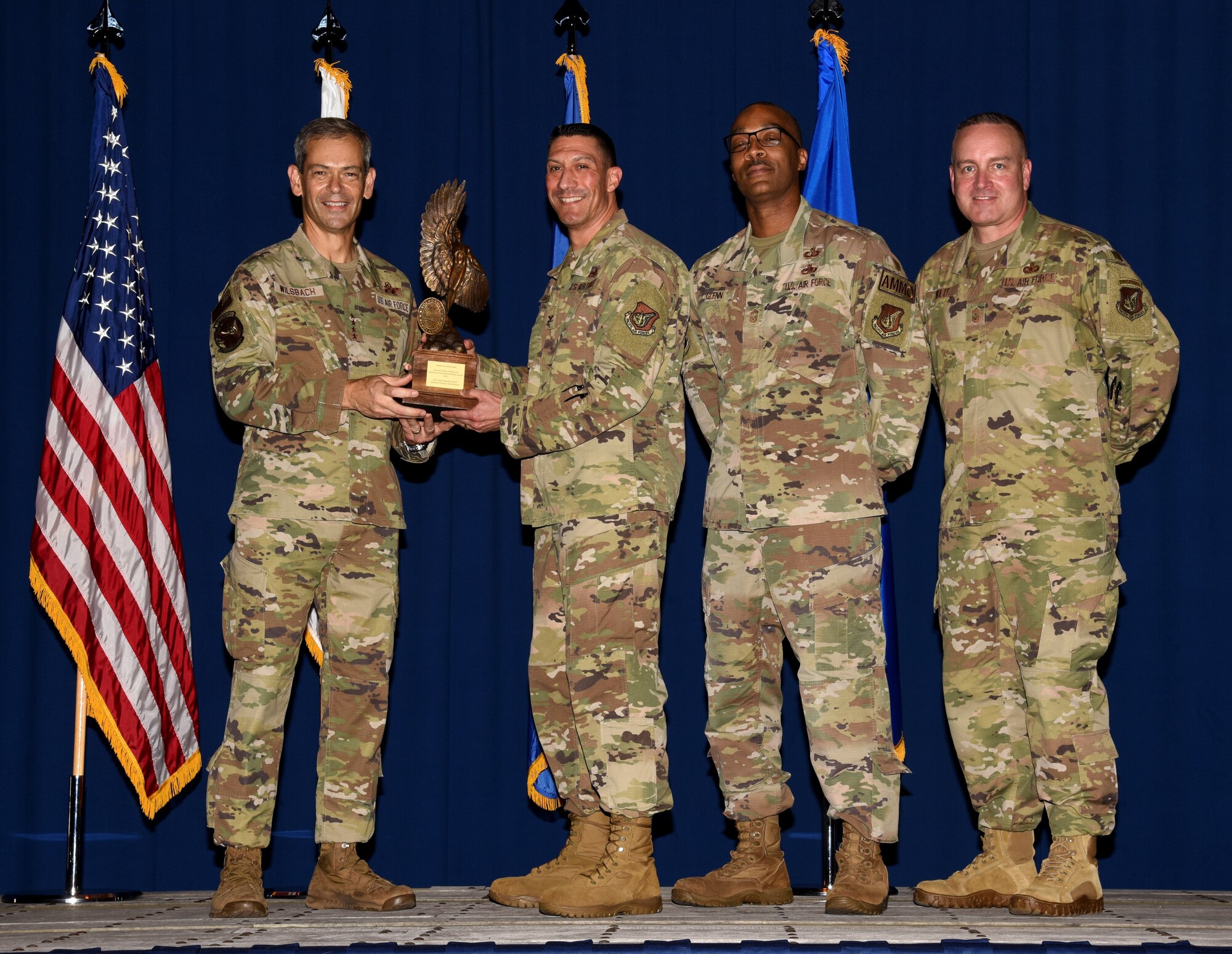 Service members receives a trophy and poses for a photo.