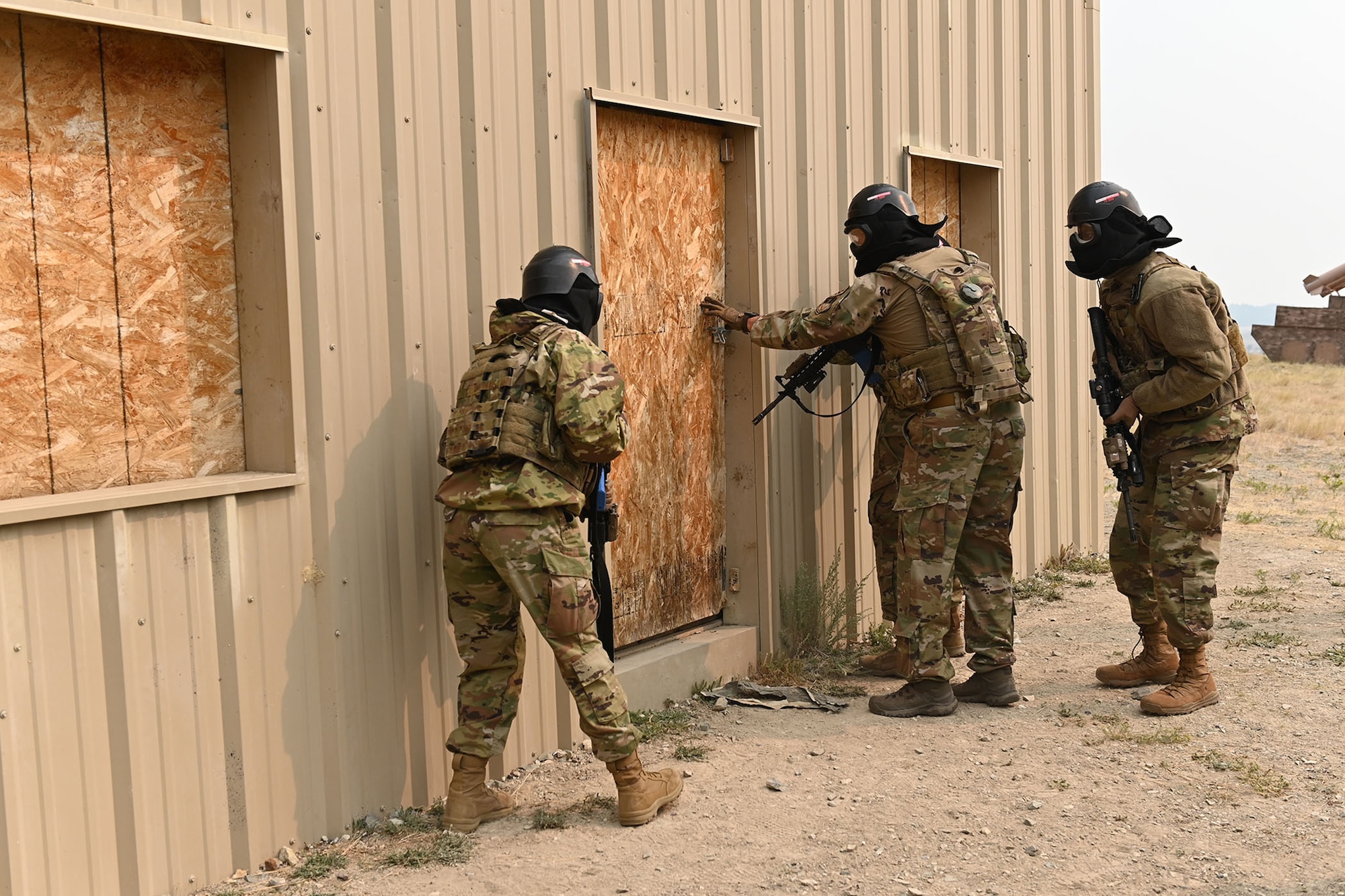 Defenders from the 841st Missile Security Forces Squadron prepare to breach a door Aug. 17, 2021, during a training exercise at the firing range village on Fort Harrison, Mont. The breach teams consisted of four defenders, who move through the building in specific formations to maximize vision and lethality. The training exercise is designed to teach defenders the proper technique of moving as a breaching unit, while simultaneously increasing confidence in stressful situations. (U.S. Air Force photo by Airman Elijah Van Zandt)