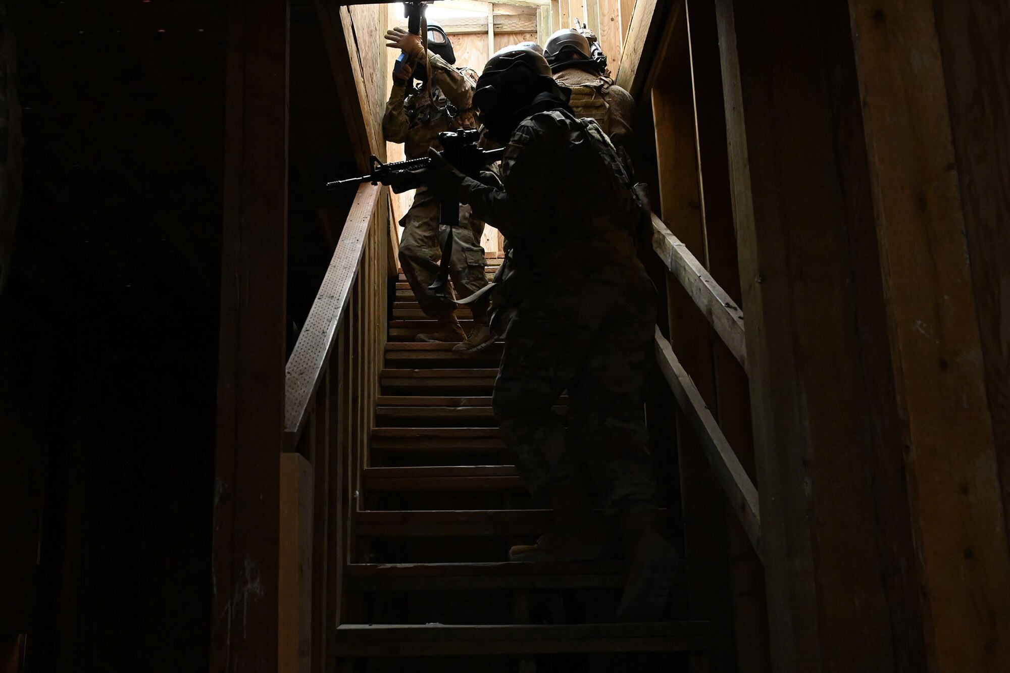 Defenders from the 841st Missile Security Forces Squadron navigate a dark staircase during a breaching exercise Aug. 17, 2021, at the firing range village on Fort Harrison, Mont. Simulated hostages and enemy combatants were inside the building, which required defenders to use critical weapon skills and decision-making while performing proper unit formations. (U.S. Air Force photo by Airman Elijah Van Zandt)