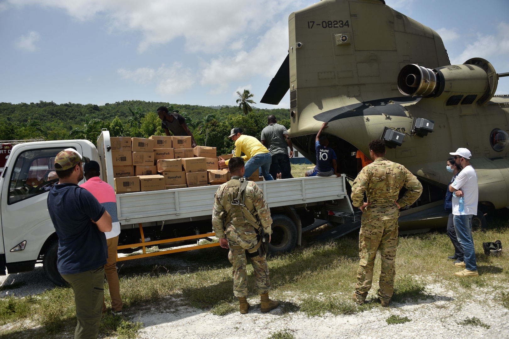 People unload boxes from the cargo hold of a helicopter into a truck.