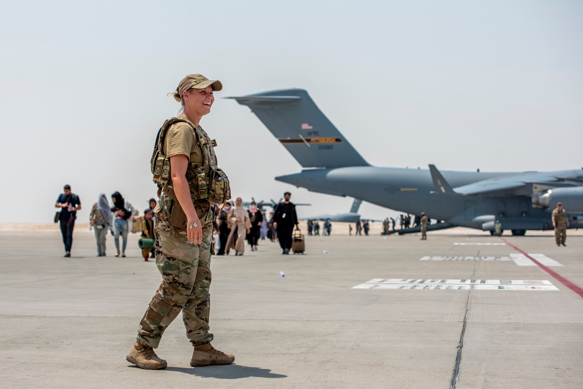 A member from the 379th Air Expeditionary Wing guides qualified evacuees debarking a C-17 Globemaster lll Aug. 23, 2021, at Al Udeid Air Base, Qatar.