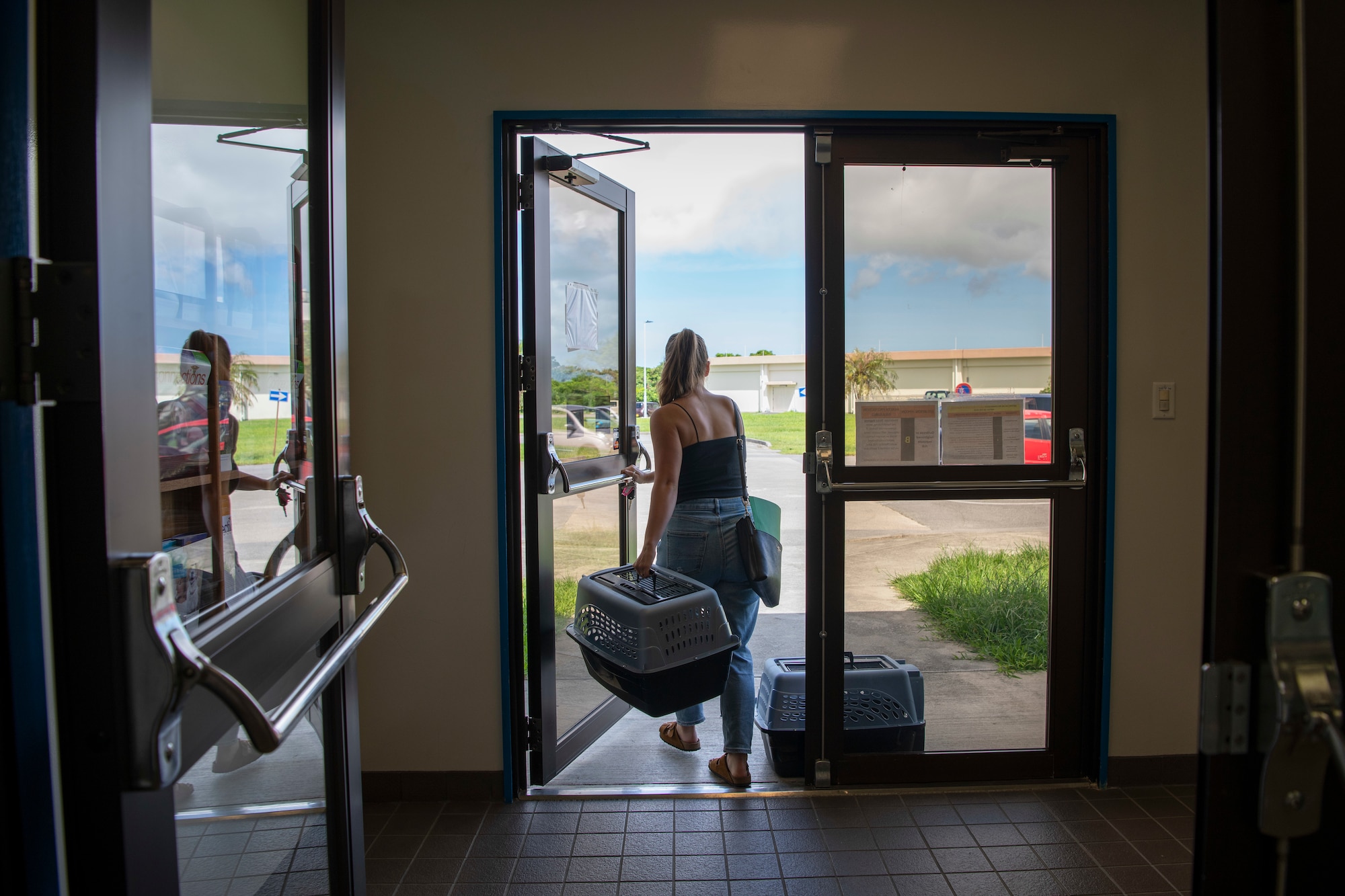 Katie Lambie, dependent, leaves the Kadena Air Base Okinawa Veterinary Activity with her two cats, Pepper and Matilda, after having them equipped with microchips, Aug. 25, 2021. The microchip injection comes preloaded in a sterile applicator and is injected under the loose skin between the shoulder blades. The process takes only a few seconds. (U.S. Air Force photo by Staff Sgt. Rhett Isbell)
