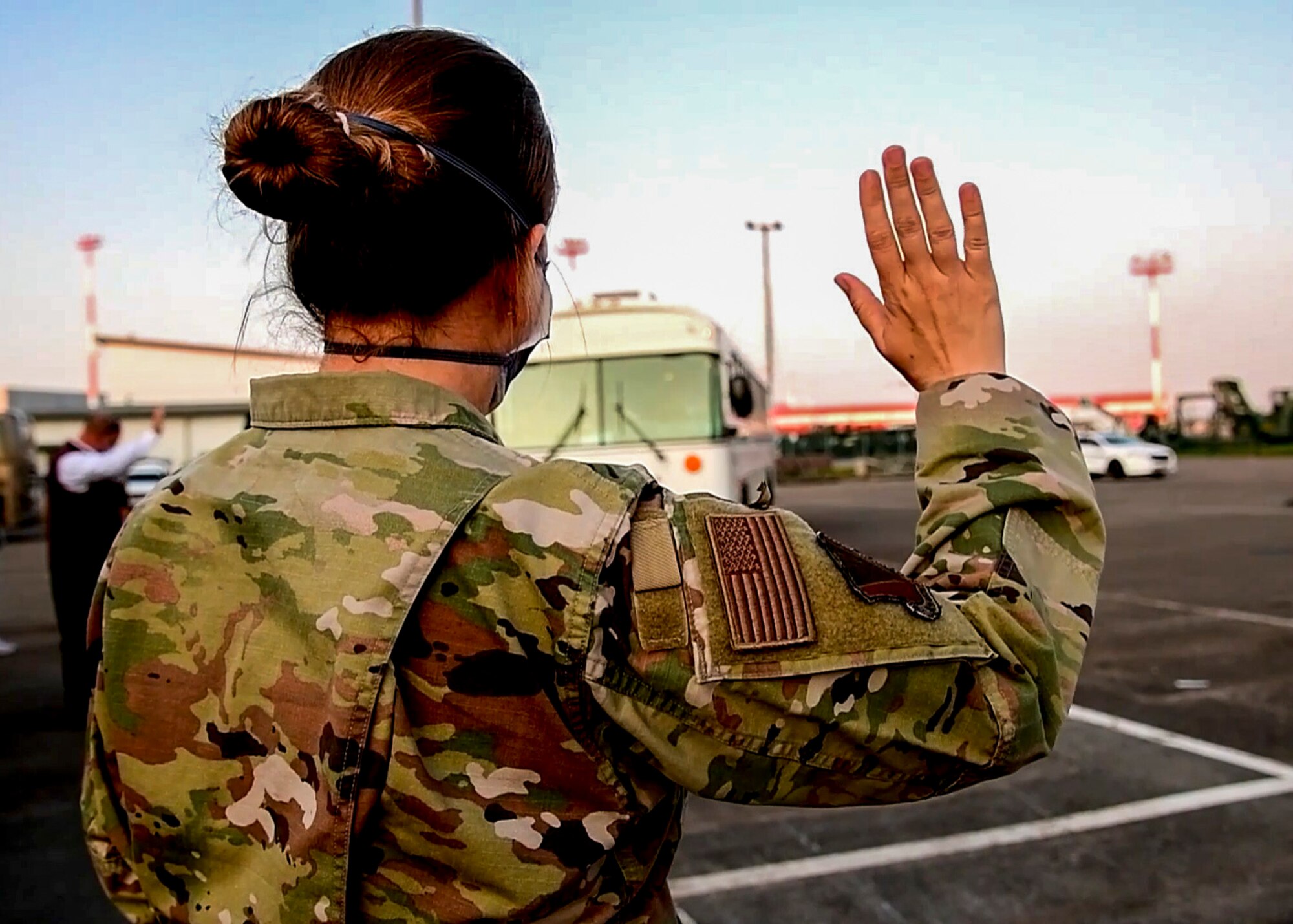 Airman waves at first bus of evacuees.