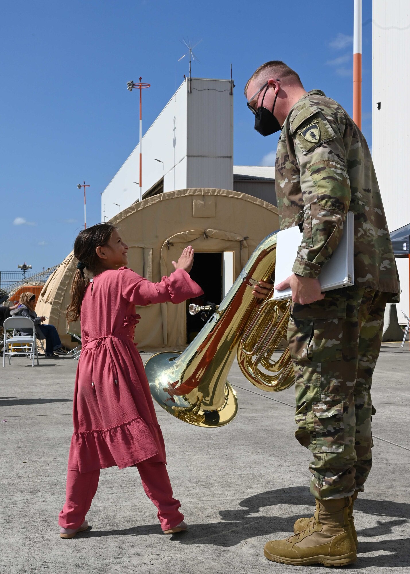 Girl evacuee interacts with tuba player.