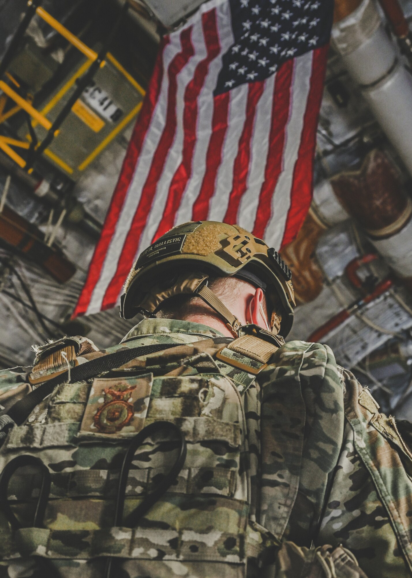 Airman stands under American flag.