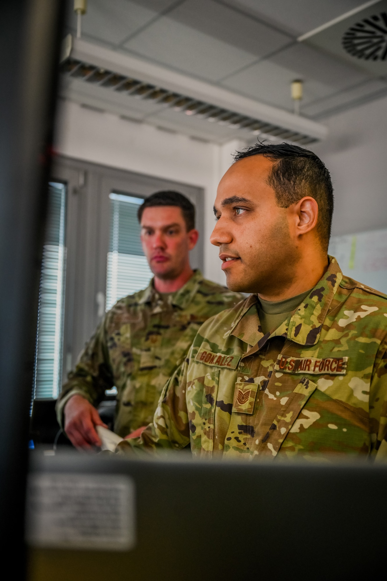 Airmen work at desks.