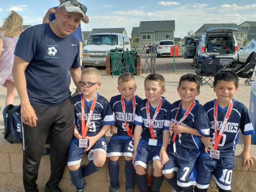 A coach poses for a photo with his youth soccer team.