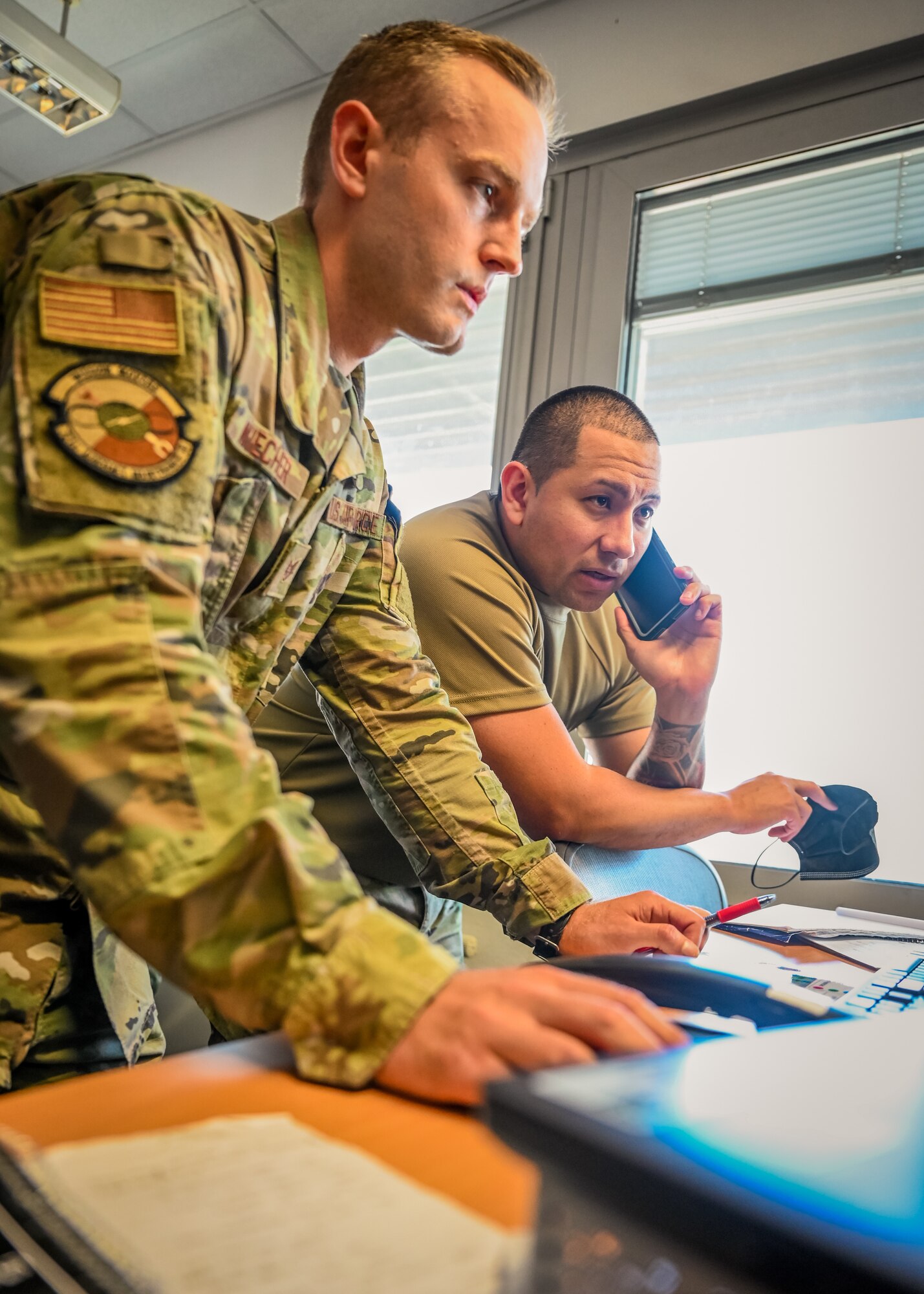 Airmen work at desks.