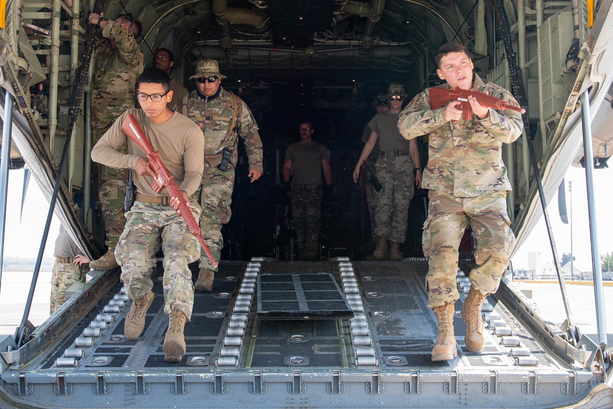 Airmen with rifles exiting aircraft.