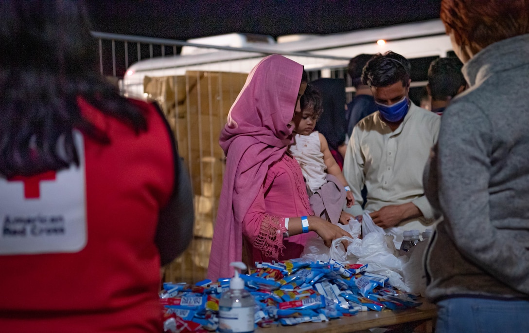 Members of the American Red Cross issue food and water to Afghan evacuees during Operation Allies Refuge, Aug. 20, 2021. Ramstein Air Base is providing safe, temporary lodging for evacuees from Afghanistan as part of the operation. The operation is facilitating the quick, safe evacuation of U.S. citizens, Special Immigrant Visa applicants and other at-risk Afghans from Afghanistan. Evacuees will receive support, such as temporary lodging, food and water and access to medical care as well as religious care at Ramstein AB while preparing for onward movements to their final destination.