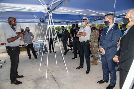 Man briefing group of people under a canopy.