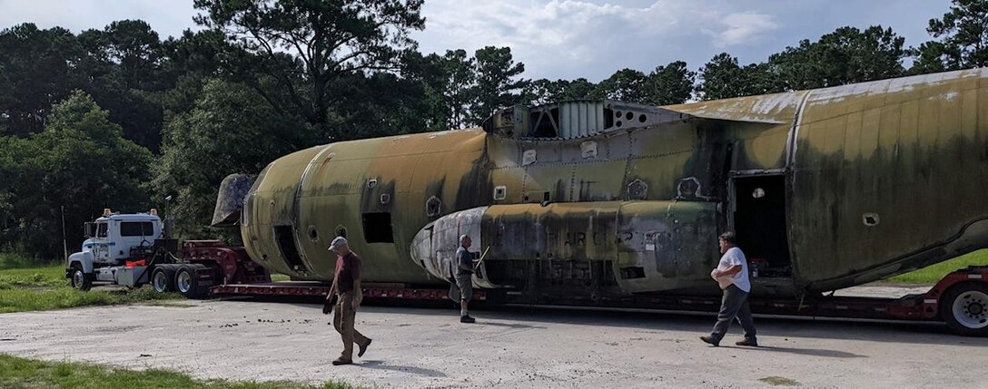 Individuals walk next to fuselage of a disable C-130