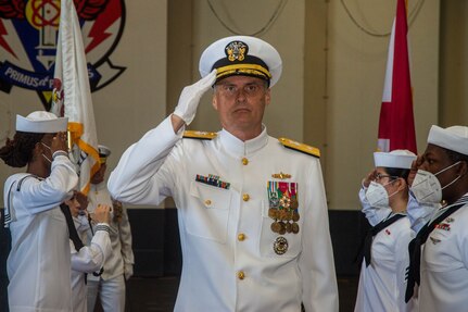 Rear Adm. Curt Renshaw renders honors while passing through sideboys during a change of command ceremony for Commander, Carrier Strike Group (CSG) 8 in the hangar bay of the Nimitz-class aircraft carrier USS Harry S. Truman (CVN 75).