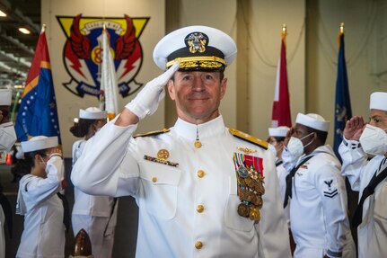 Rear Adm. Ryan Scholl, commander, Carrier Strike Group (CSG) 8 renders honors while passing through sideboys during a change of command ceremony for CSG-8 in the hangar bay of the Nimitz-class aircraft carrier USS Harry S. Truman (CVN 75).