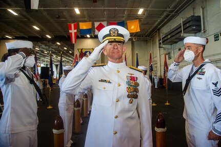 Vice Adm. Daniel Dwyer, commander, U.S. Second Fleet, renders honors while passing through sideboys during a change of command ceremony for Commander, Carrier Strike Group (CSG) 8 in the hangar bay of the Nimitz-class aircraft carrier USS Harry S. Truman (CVN 75).