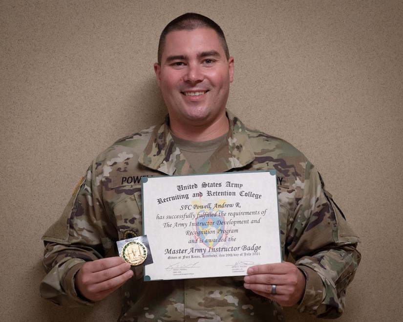 man in u.s. army uniform is presented with an award in front of a classroom.
