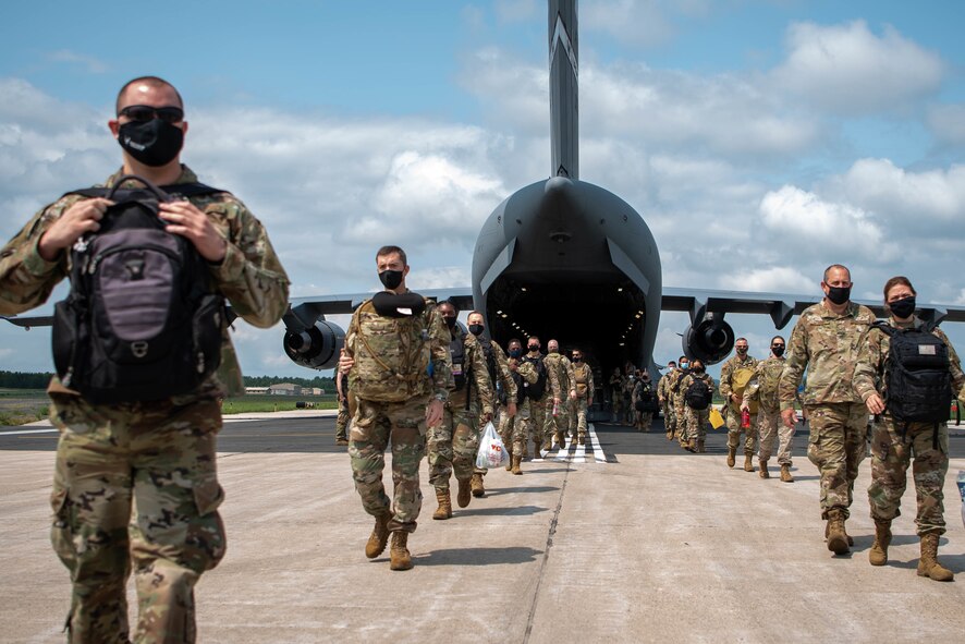 Photo of Airmen walking out of a plane with bags