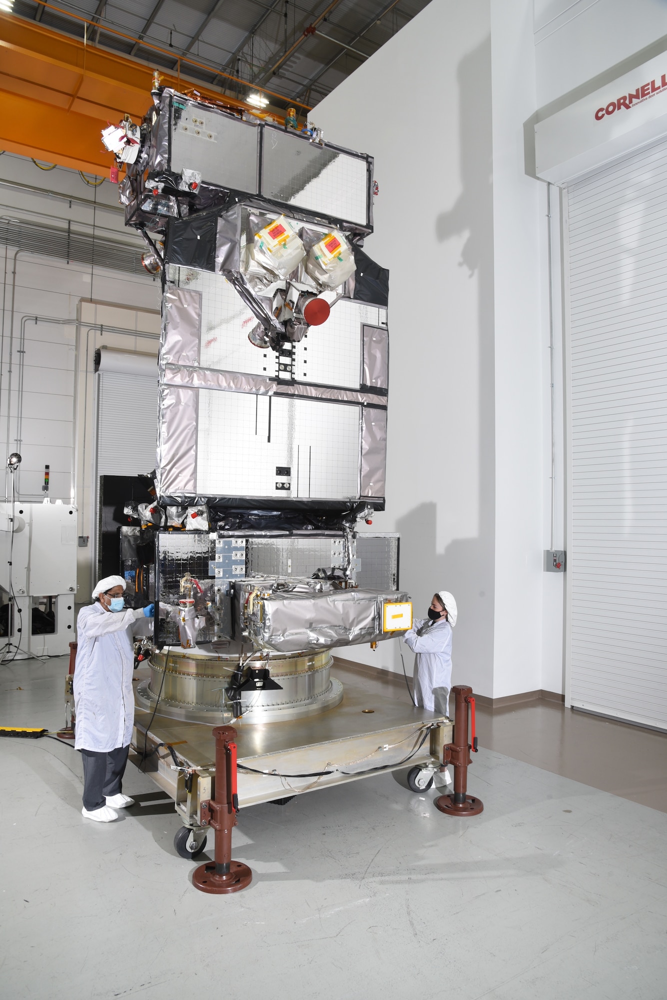 photo of two personnel in lab coats with a satellite inside a building