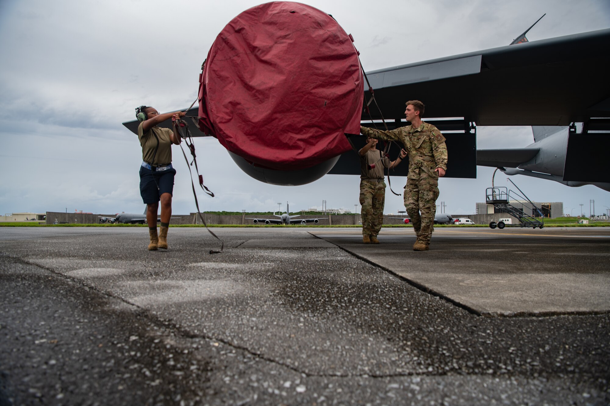 U.S. Air Force Staff Sgt. Destini Edmond(left), 909th Aircraft Maintenance Unit guidance and control craftsman, Maj. Elliott Sahli (center), 909th Air Refueling Squadron instructor pilot, and Capt. Daniel Thomas (right), 909th ARS pilot, remove an engine cover from a KC-135 Stratotanker at Kadena Air Base, Japan, in support of Large Scale Global Exercise 21, Aug. 18, 2021. LSGE21 participants have the opportunity to further enhance their capability and proficiency to respond to shared challenges as part of a joint or combined effort. (U.S. Air Force photo by Tech. Sgt. Micaiah Anthony)