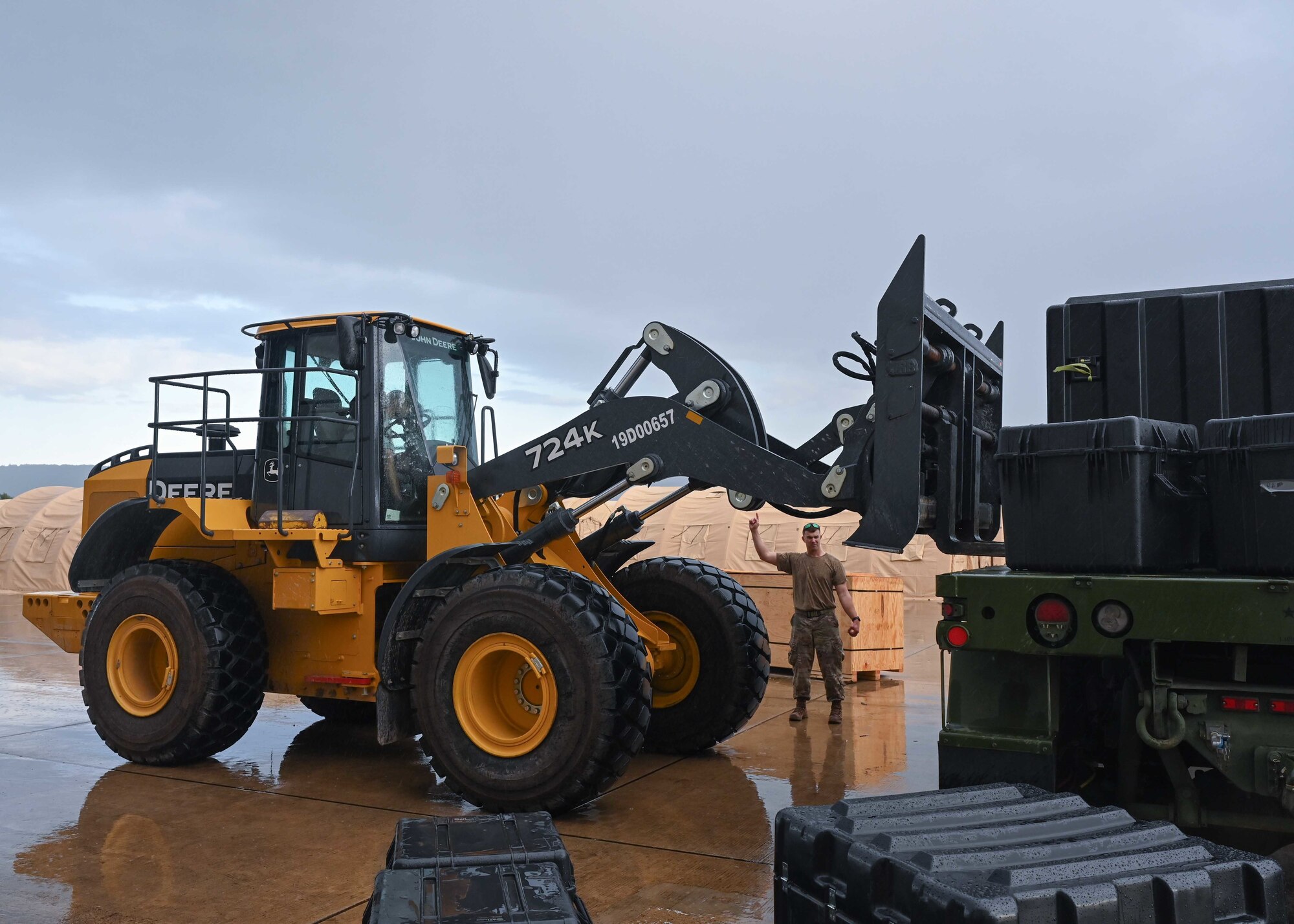 Airman moves heavy equipment with large working vehicle.