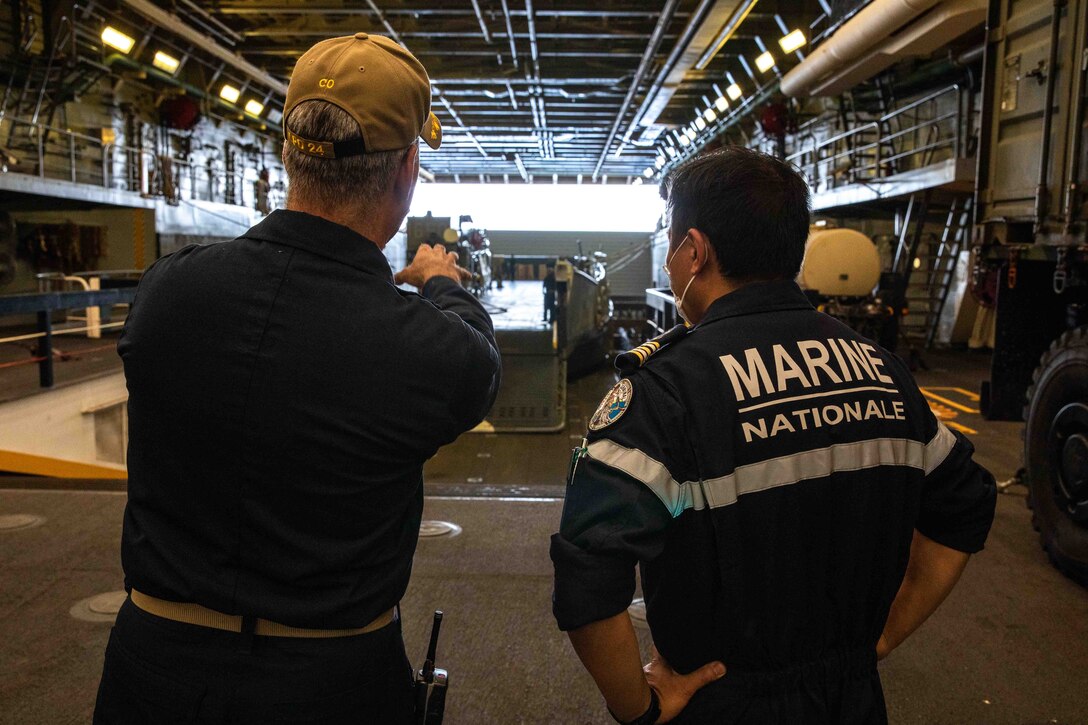 Capt. Eric Kellum, commanding officer of USS Arlington (LPD 24), explains the ship’s well deck capabilities to French navy frigate Capt. Chun Jen Fang, commandant of the Flor’al-class frigate FS Germinal (F735), Aug. 24, 2021.