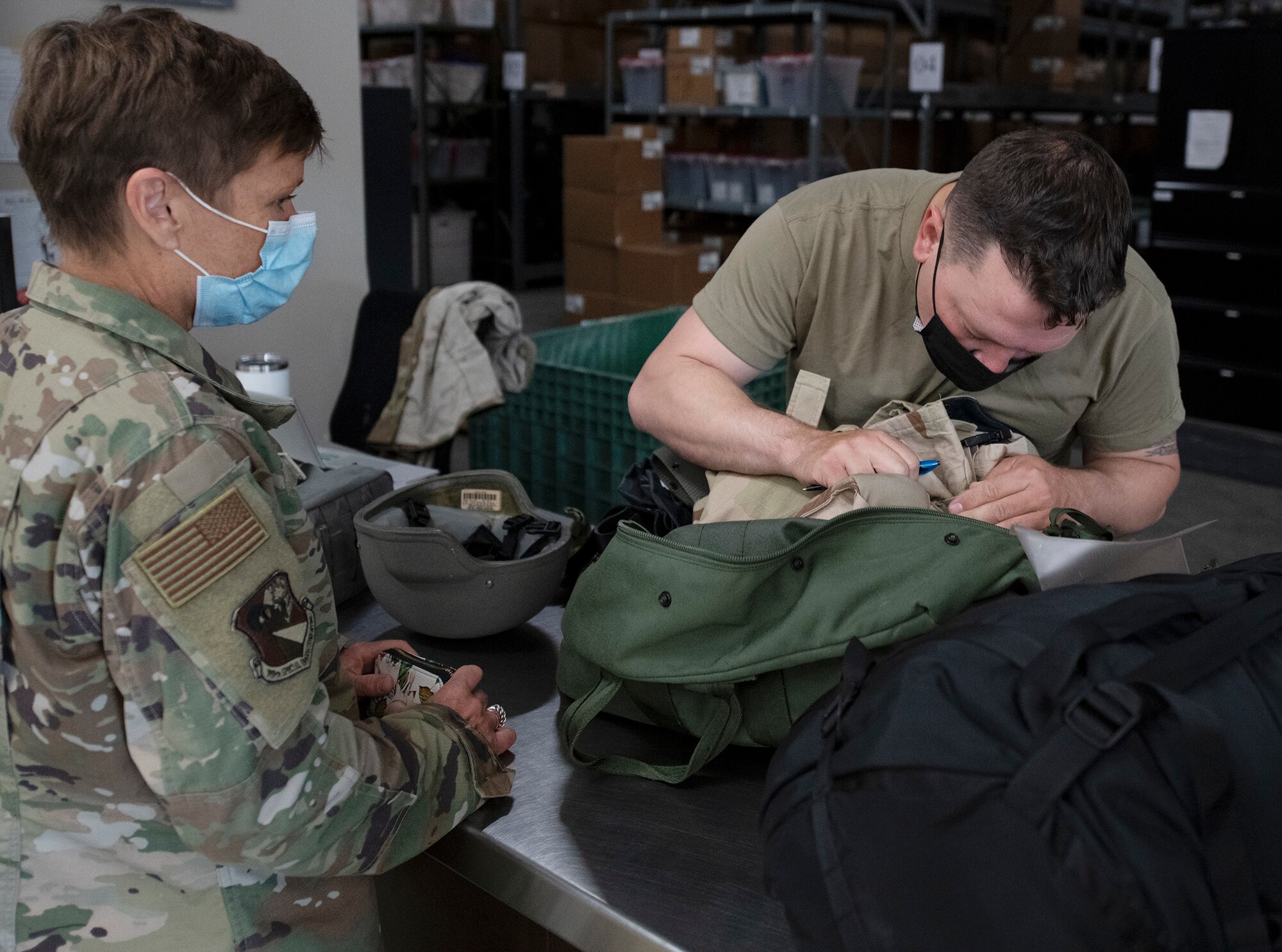 Photo of Airman issuing gear to another Airman