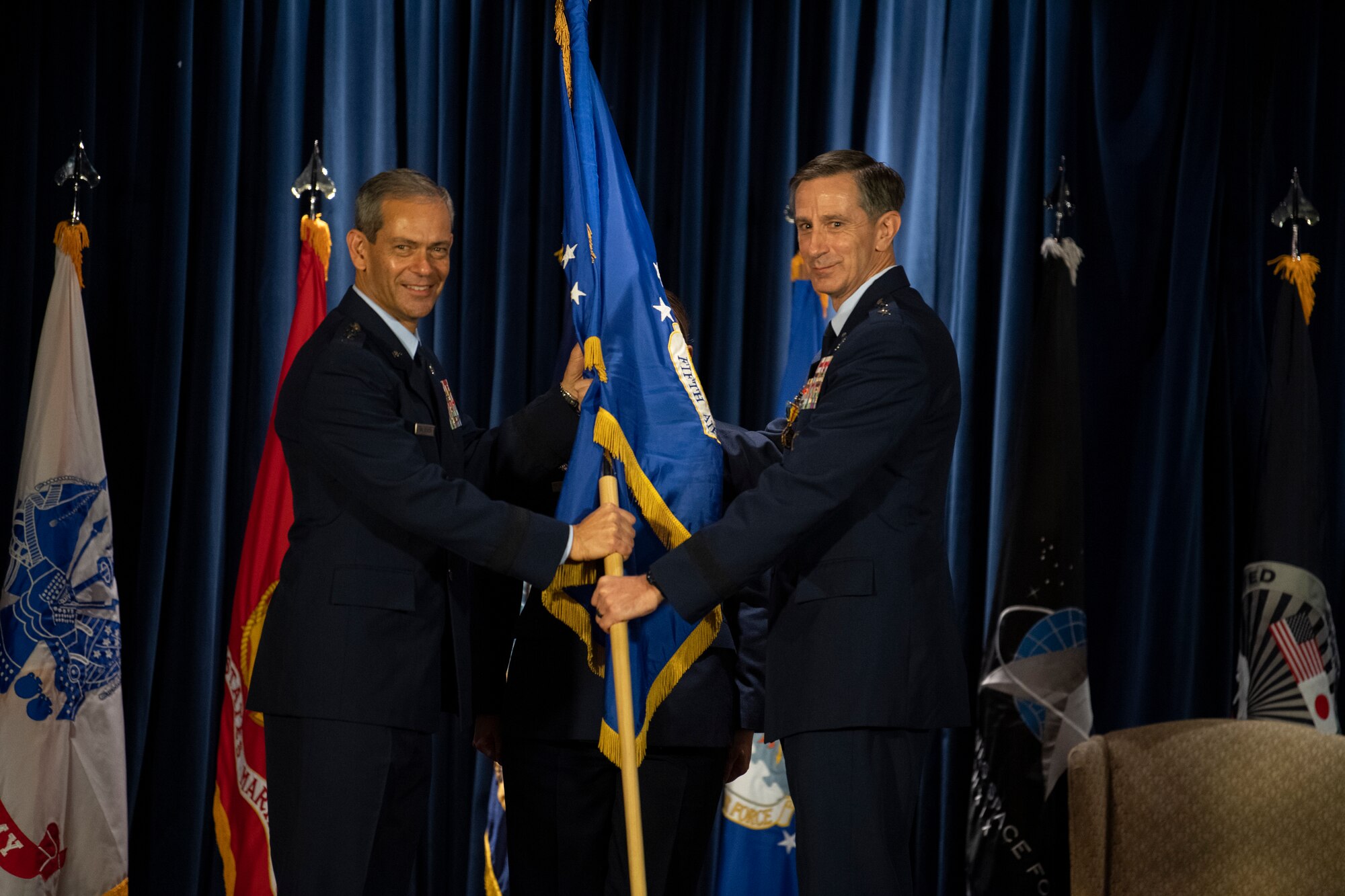 U.S. Air Force Gen. Ken S. Wilsbach, left, Pacific Air Forces commander, receives the 5th Air Force guidon from Lt. Gen. Kevin B. Schneider, right, U.S. Forces Japan and 5th Air Force outgoing commander, during the USFJ and 5th AF change of command ceremony at Yokota Air Base, Japan, Aug. 27, 2021.