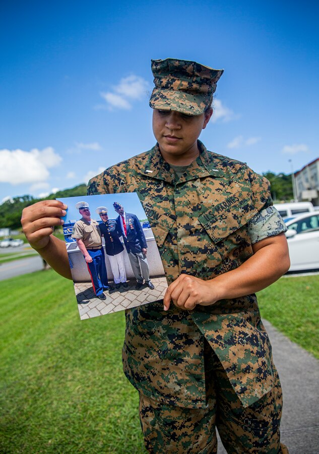 U.S. Marine Corps 1st Lt. Ashleigh Fairow, the Communication Strategy and Operations officer with Headquarters and Support Battalion, Marine Corps Installations Pacific, examines a photo of her family on Camp Foster, Okinawa, Japan, Aug. 27, 2021. A native of Jacksonville, North Carolina, Fairow became a commissioned officer in 2019 after earning a Bachelor of Science in English Studies and graduating from the U.S. Naval Academy at the age of 23. Her grandfather, retired Sgt. Ivor Griffin, enlisted in the Marine Corps in 1945, making history as he became one of the 20,000 African-Americans trained to become Marines at Montford Point Camp, Camp Lejeune, North Carolina. (U.S. Marine Corps photo by Lance Cpl. Alex Fairchild)