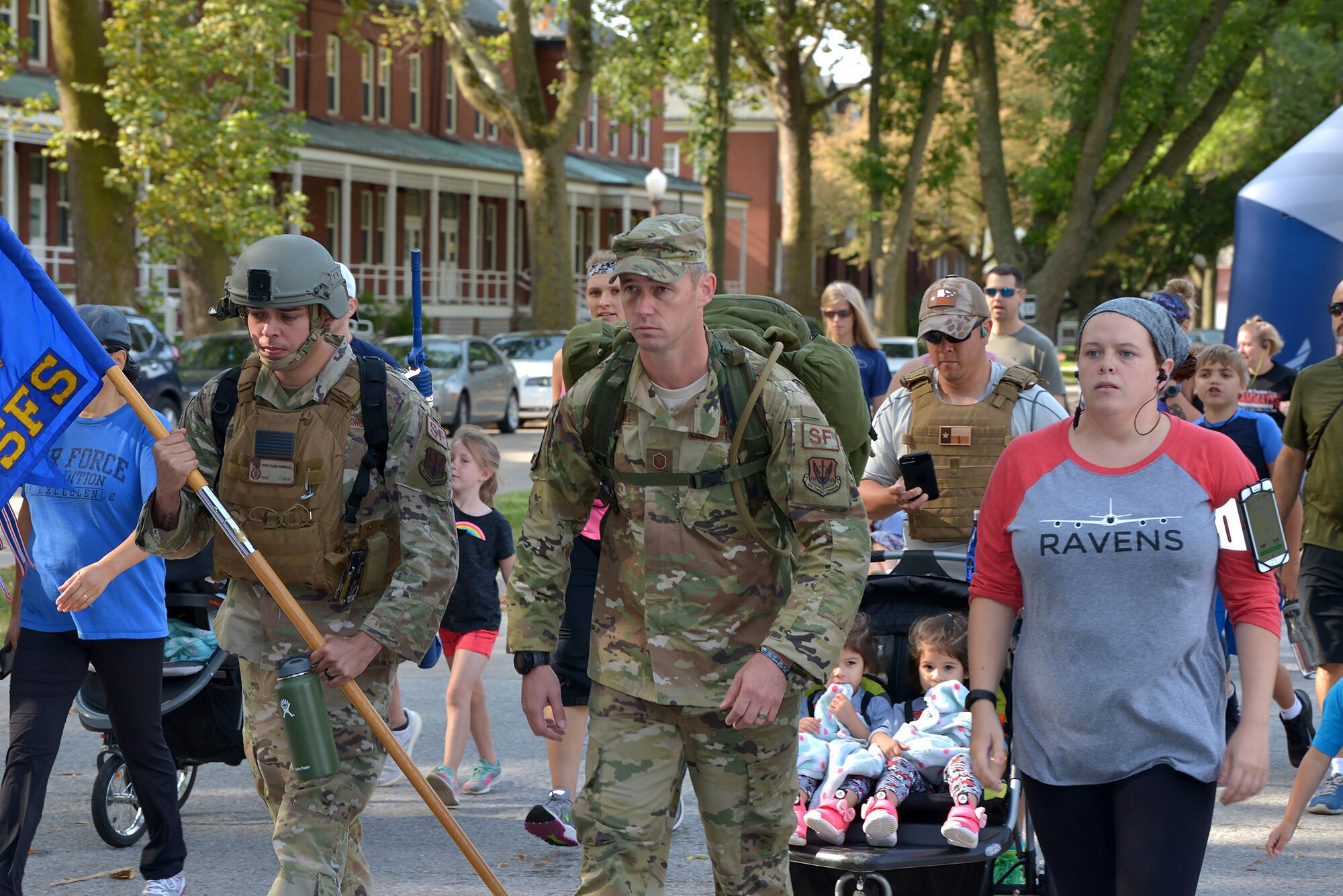 Airmen in uniform, civilians and children walking in large group