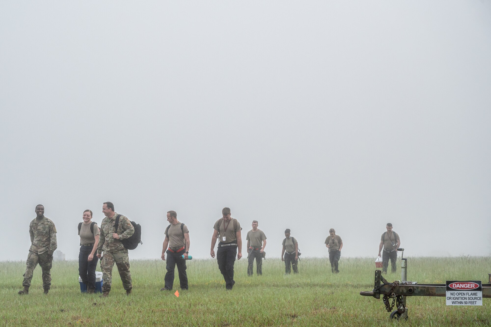 A photo of Airmen walking in a field in the mist.
