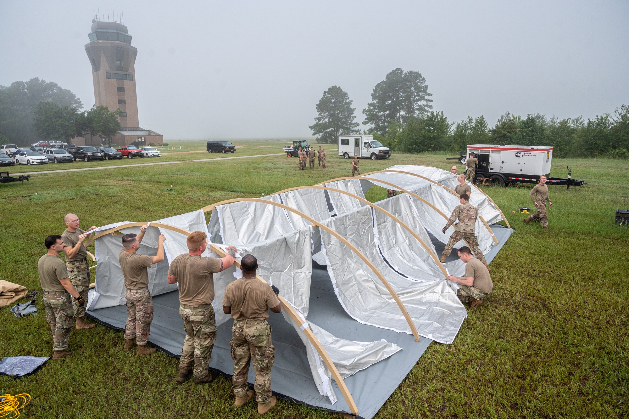 A picture of Airmen assembling a temporary shelter in a field.