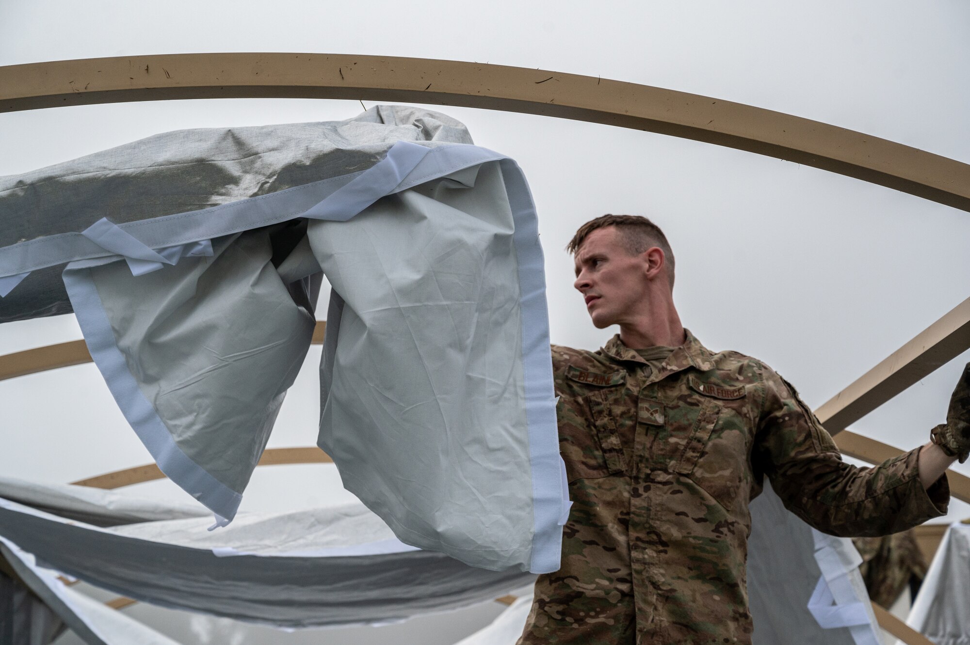 A picture of an Airman assembling a tent.