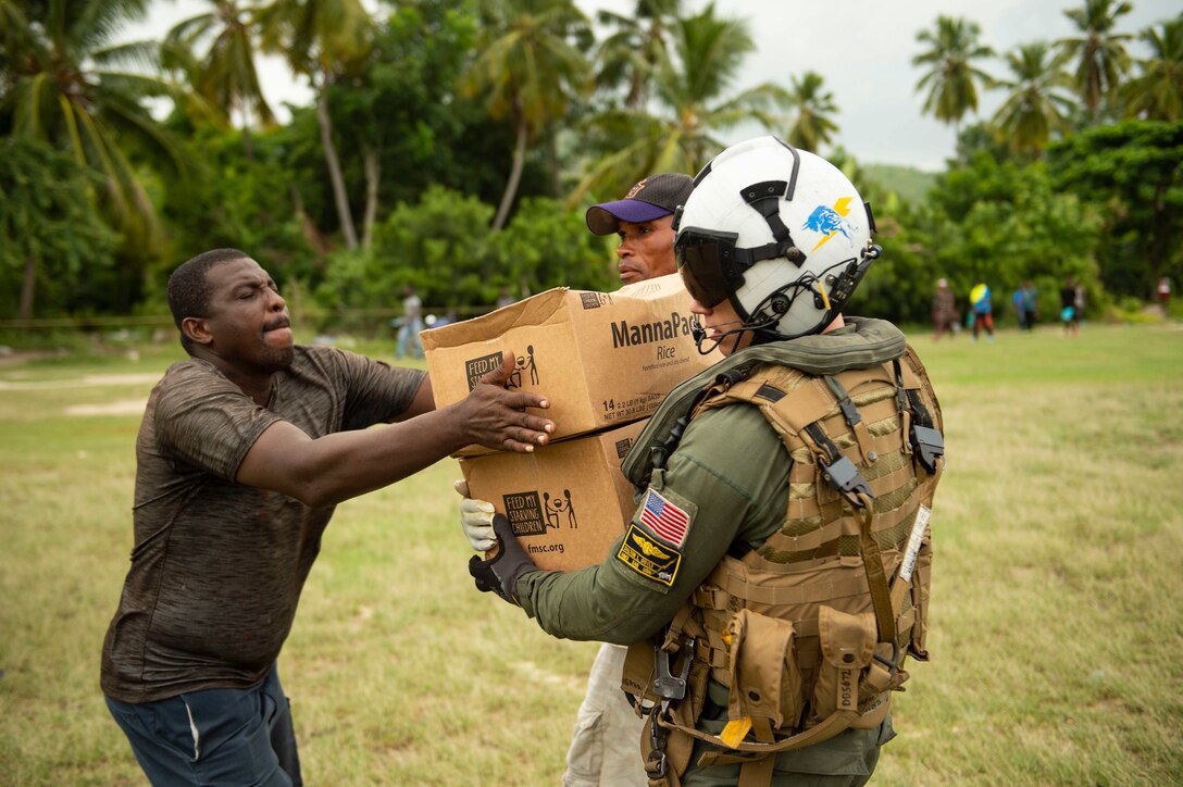 HSC-26 distributes food aid to Haitian citizens during a humanitarian aid mission.