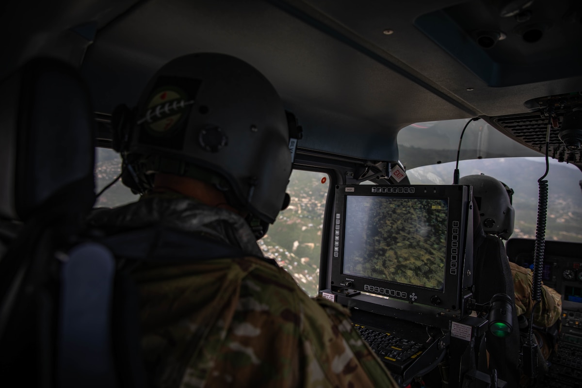 Sgt. Francisco Silva, crew chief of the UH-72 helicopter, from the Puerto Rico Army National Guard Aviation operates the aircraft’s MX-15 camera during a flight over the community of L’Asile, Haiti, Aug. 24, 2021.
