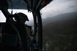Chief Warrant Officer three (CW3) Norberto Martinez from the Puerto Rico Army National Guard Aviation looks down the right side of the aircraft during a reconnaissance flight over La Hatte, Haiti, Aug. 25, 2021.